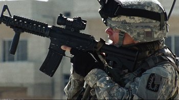 Movie still from “The Hurt Locker” (2008), directed by Kathryn Bigelow – A soldier is holding a rifle and aiming it; Medium shot, Low angle