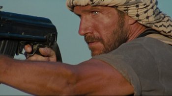 Movie still from “The Hurt Locker” (2008), directed by Kathryn Bigelow – A person holding a gun; Close Up shot, Over the shoulder angle