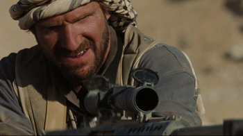 Movie still from “The Hurt Locker” (2008), directed by Kathryn Bigelow – A person with a rifle; Close Up shot, Over the shoulder angle
