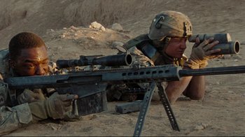 Movie still from “The Hurt Locker” (2008), directed by Kathryn Bigelow – A soldier is sitting on the ground with a rifle; Medium shot, Low angle