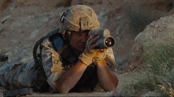 Movie still from “The Hurt Locker” (2008), directed by Kathryn Bigelow – A soldier is laying on the ground taking a picture; Medium shot, High angle