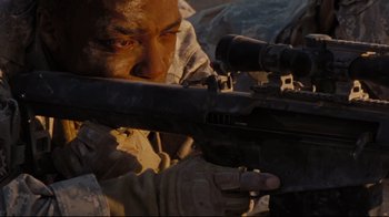 Movie still from “The Hurt Locker” (2008), directed by Kathryn Bigelow – A man in fatigues is holding a rifle and aiming it; Extreme Close Up shot, High angle