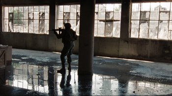 Movie still from “The Hurt Locker” (2008), directed by Kathryn Bigelow – A person in a room holding a gun; Extreme Wide shot, Low angle
