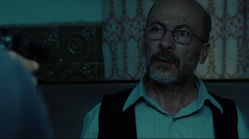 Movie still from “The Hurt Locker” (2008), directed by Kathryn Bigelow – An older man wearing glasses and a white shirt; Close Up shot, Low angle