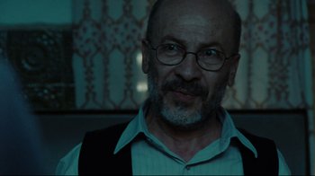 Movie still from “The Hurt Locker” (2008), directed by Kathryn Bigelow – An older man wearing glasses and a white shirt; Close Up shot, Over the shoulder angle