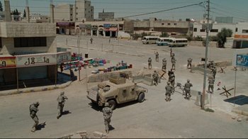 Movie still from “The Hurt Locker” (2008), directed by Kathryn Bigelow – A group of men standing next to each other in the middle of a street; Extreme Wide shot, High angle