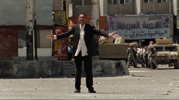 Movie still from “The Hurt Locker” (2008), directed by Kathryn Bigelow – A man in a black suit and white shirt standing in the middle of a street; Wide shot, Low angle