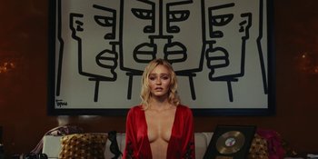 Movie still from “The Idol” (2023), directed by Sam Levinson – A woman in a red robe standing in front of a painting; Medium shot, Low angle