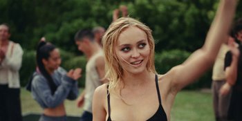 Movie still from “The Idol” (2023), directed by Sam Levinson – A young woman with blonde hair is smiling for the camera; Close Up shot, Over the shoulder angle