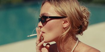 Movie still from “The Idol” (2023), directed by Sam Levinson – A beautiful woman wearing sunglasses and smoking a cigarette; Close Up shot, Low angle