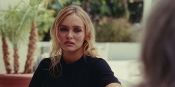 Movie still from “The Idol” (2023), directed by Sam Levinson – A beautiful blonde haired woman wearing a black shirt; Close Up shot, Over the shoulder angle