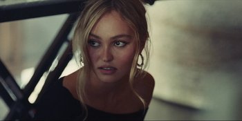 Movie still from “The Idol” (2023), directed by Sam Levinson – A beautiful blonde haired woman with blue eyes looking at the camera; Close Up shot, High angle