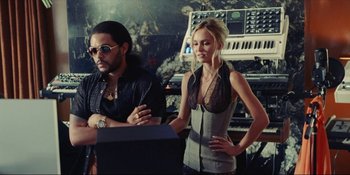 Movie still from “The Idol” (2023), directed by Sam Levinson – A man and a woman are standing next to a computer; Medium shot, Low angle