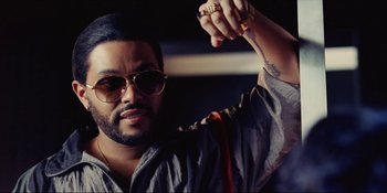 Movie still from “The Idol” (2023), directed by Sam Levinson – A person wearing sunglasses and a tie; Close Up shot, Low angle