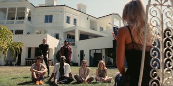 Movie still from “The Idol” (2023), directed by Sam Levinson – A group of people sitting in the grass; Wide shot, High angle