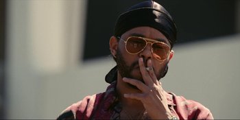 Movie still from “The Idol” (2023), directed by Sam Levinson – A man with a black hat smoking a cigarette; Close Up shot, Low angle