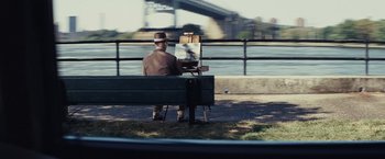Movie still from “Bridge of Spies” (2015), directed by Steven Spielberg – A man sitting on top of a wooden bench painting; Wide shot, Over the shoulder angle