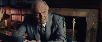 Movie still from “Bridge of Spies” (2015), directed by Steven Spielberg – An older man wearing a suit and tie sitting in a chair; Close Up shot, Over the shoulder angle