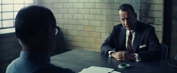 Movie still from “Bridge of Spies” (2015), directed by Steven Spielberg – A man sitting at a table in front of another man; Close Up shot, Over the shoulder angle