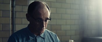 Movie still from “Bridge of Spies” (2015), directed by Steven Spielberg – An older man wearing glasses and a blue shirt; Close Up shot, Over the shoulder angle