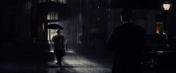 Movie still from “Bridge of Spies” (2015), directed by Steven Spielberg – A man holding an umbrella while standing in the rain; Wide shot, Over the shoulder angle