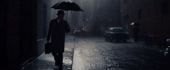 Movie still from “Bridge of Spies” (2015), directed by Steven Spielberg – A man walking down a street holding an umbrella; Wide shot, Low angle