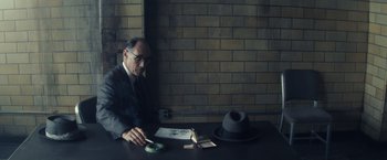 Movie still from “Bridge of Spies” (2015), directed by Steven Spielberg – A man sitting at a table in front of a brick wall; Medium shot, High angle