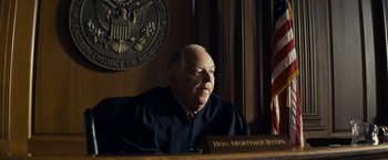 Movie still from “Bridge of Spies” (2015), directed by Steven Spielberg – An older man sitting in front of a judge's bench; Medium shot, Low angle