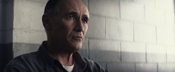 Movie still from “Bridge of Spies” (2015), directed by Steven Spielberg – An older man looking into the distance in front of a brick wall; Close Up shot, Low angle