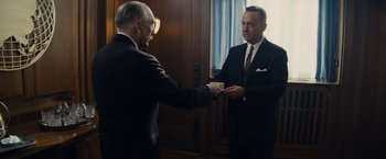 Movie still from “Bridge of Spies” (2015), directed by Steven Spielberg – Two men in business suits are exchanging business cards; Medium shot, Over the shoulder angle