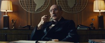 Movie still from “Bridge of Spies” (2015), directed by Steven Spielberg – An older man sitting at a table smoking a pipe; Close Up shot, Low angle