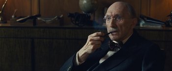 Movie still from “Bridge of Spies” (2015), directed by Steven Spielberg – An older man smoking a pipe while wearing a suit; Close Up shot, Low angle