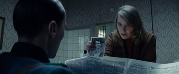 Movie still from “Bridge of Spies” (2015), directed by Steven Spielberg – A woman looking at a newspaper with a picture of a man; Close Up shot, Over the shoulder angle