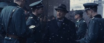 Movie still from “Bridge of Spies” (2015), directed by Steven Spielberg – A man in a suit and hat talking to another man in a suit and hat; Medium shot, Over the shoulder angle