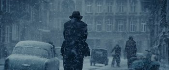 Movie still from “Bridge of Spies” (2015), directed by Steven Spielberg – A man in a black coat and a black hat walking in the snow; Wide shot, Over the shoulder angle