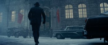 Movie still from “Bridge of Spies” (2015), directed by Steven Spielberg – A man walking in the snow near a building; Wide shot, Low angle