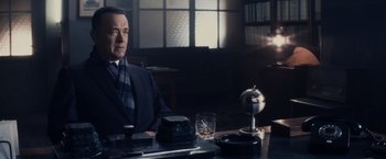 Movie still from “Bridge of Spies” (2015), directed by Steven Spielberg – A man sitting at a table with a glass of whiskey; Medium shot, Over the shoulder angle