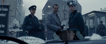 Movie still from “Bridge of Spies” (2015), directed by Steven Spielberg – A group of men standing next to each other in front of a building; Medium shot, Over the shoulder angle