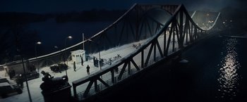 Movie still from “Bridge of Spies” (2015), directed by Steven Spielberg – People are standing on a bridge over a river at night; Extreme Wide shot, High angle