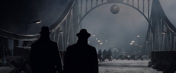Movie still from “Bridge of Spies” (2015), directed by Steven Spielberg – A group of people walking across a bridge at night; Wide shot, Over the shoulder angle