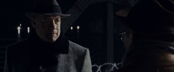 Movie still from “Bridge of Spies” (2015), directed by Steven Spielberg – A man wearing a hat and a coat standing in front of barbed wire; Close Up shot, Over the shoulder angle