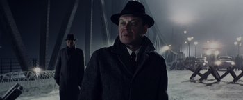 Movie still from “Bridge of Spies” (2015), directed by Steven Spielberg – A man wearing a hat and a coat standing on a bridge; Medium shot, Low angle