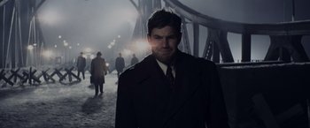 Movie still from “Bridge of Spies” (2015), directed by Steven Spielberg – A man wearing a suit and tie standing in the dark; Medium shot, Over the shoulder angle