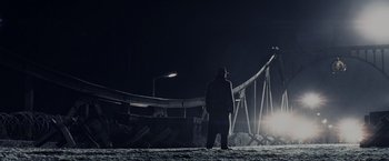 Movie still from “Bridge of Spies” (2015), directed by Steven Spielberg – A man standing in the snow at night near an amusement park; Extreme Wide shot, Low angle