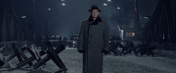 Movie still from “Bridge of Spies” (2015), directed by Steven Spielberg – A man wearing a hat and a long coat standing in the middle of a street; Medium shot, Low angle