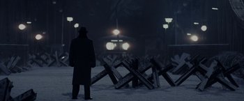 Movie still from “Bridge of Spies” (2015), directed by Steven Spielberg – A man standing in front of a fence in the dark; Wide shot, Low angle