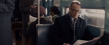 Movie still from “Bridge of Spies” (2015), directed by Steven Spielberg – A man sitting on top of a train while holding a newspaper; Medium shot, Over the shoulder angle