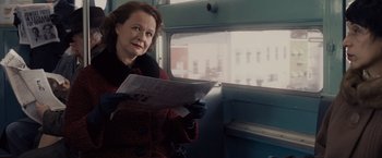 Movie still from “Bridge of Spies” (2015), directed by Steven Spielberg – A woman sitting on a train holding a newspaper; Medium shot, Over the shoulder angle