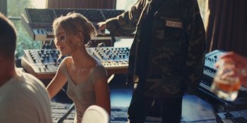 Movie still from “The Idol” (2023), directed by Sam Levinson – A woman sitting in front of a sound board while a man adjusts her hair; Medium shot, Over the shoulder angle