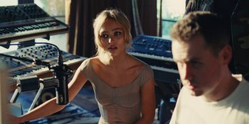 Movie still from “The Idol” (2023), directed by Sam Levinson – A woman is standing in front of a microphone; Medium shot, Over the shoulder angle